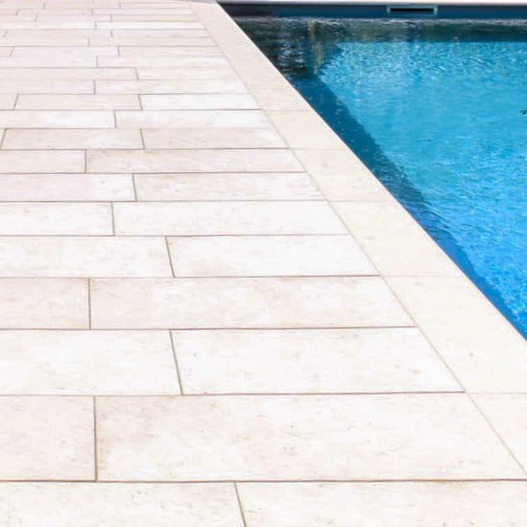 Best close-up image for Bavarian Limestone - Beige - Pool Coping. The image shows this product being used for pool coping and pool deck pavers. The surface finish shown is . Dominant colors shown are white and cream; with a beige secondary. The color mix creates a cool feeling. Solid and cloudy color patterns. Contains mineral inclusions.