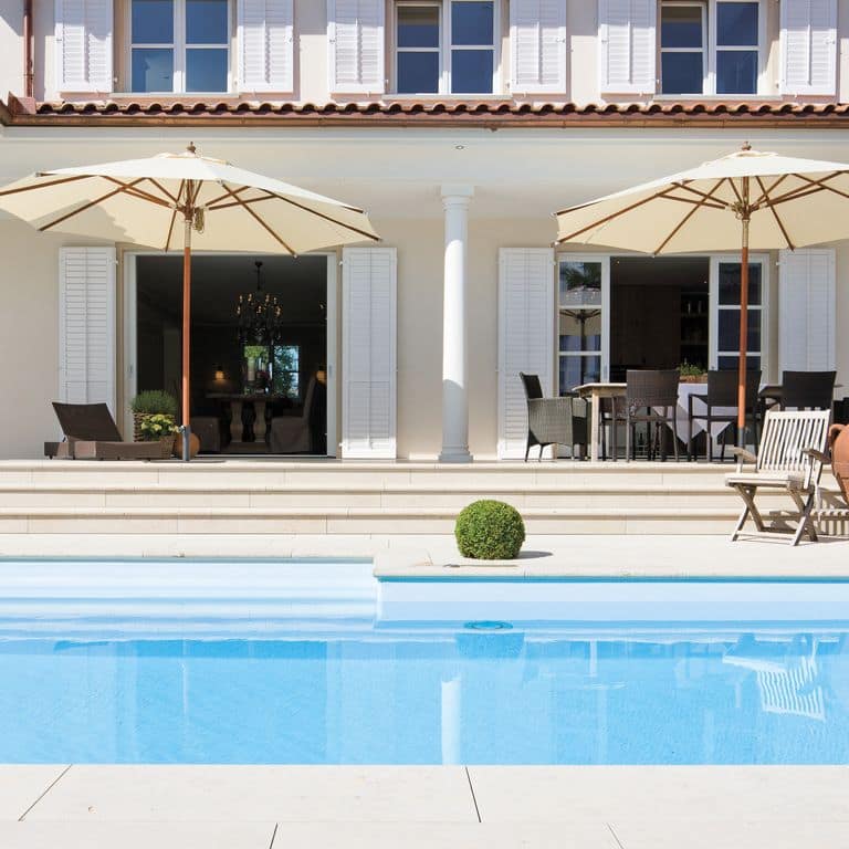 Feature image for Bavarian Limestone - Beige - Pool Coping. The image shows this product being used for pool coping and pool deck pavers. Dominant colors shown are white and cream; with a beige secondary. The color mix creates a warm feeling. Solid and cloudy color patterns. Contains mineral inclusions.