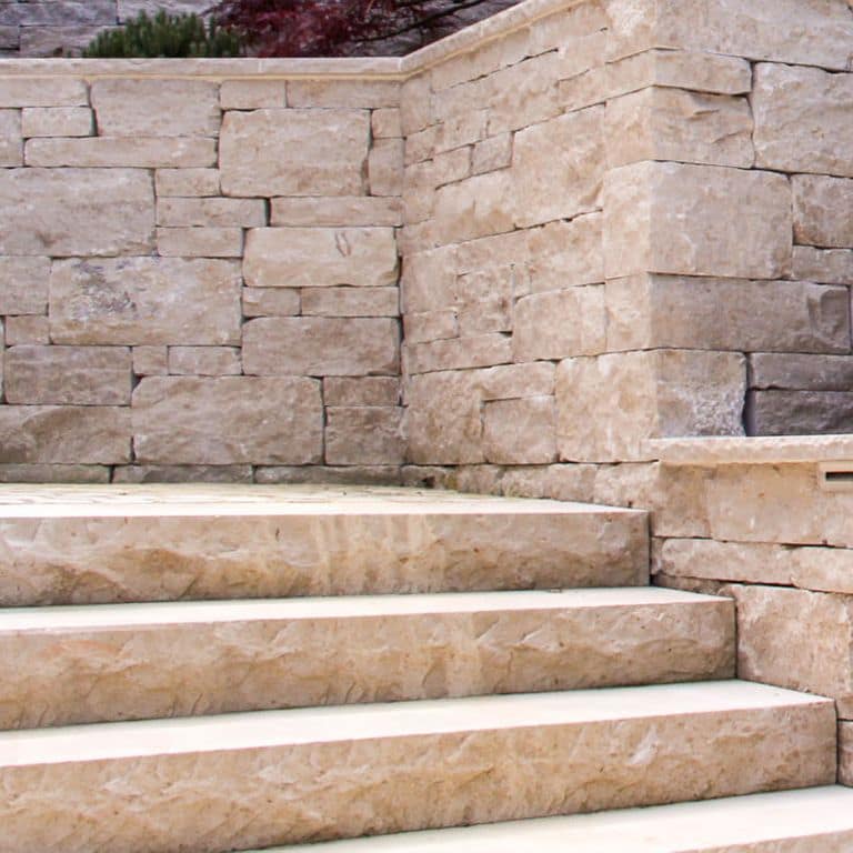 Close-up image for Bavarian Limestone Gala - Beige- Wallstone. The surface finishes shown are split-face and tumbled. Dominant colors shown are beige and tan; with brown, gray, orange/rust, pink and cream secondaries. Exhibits "movement" and the color mix creates a warm feeling. Regular, blotched and cloudy color patterns. Contains mineral inclusions.