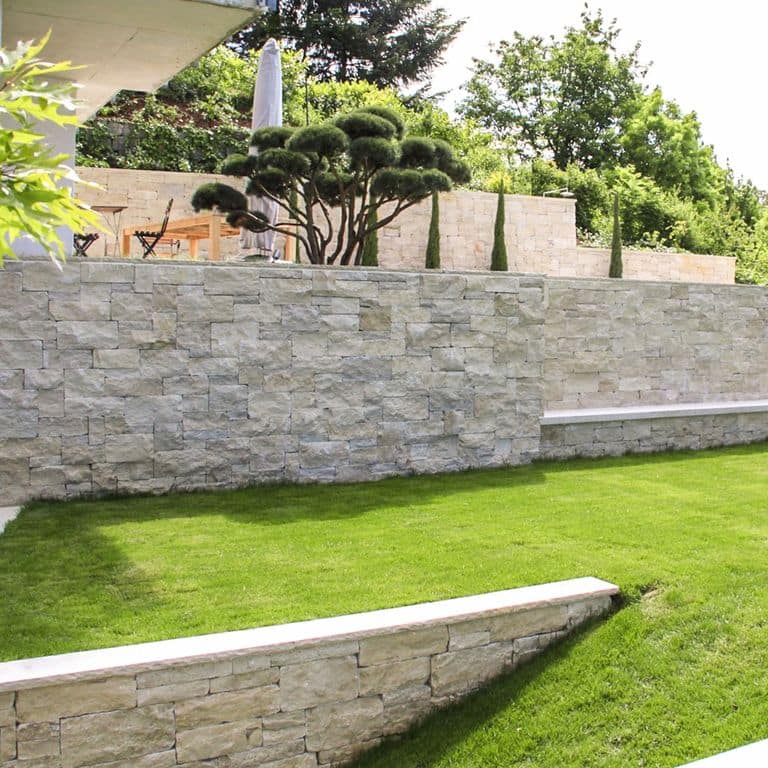 Application image for Bavarian Beige Limestone - Wallstone. The image shows this product being used in a landscape wallstone application. The surface finish shown is split-face. The dominant color shown is beige. The color mix creates a warm feeling.