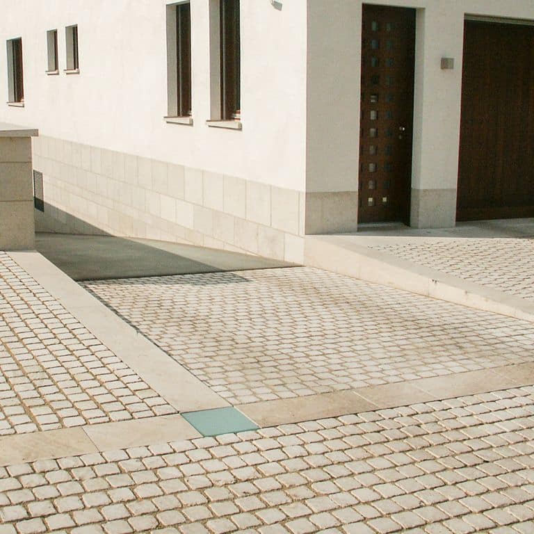Feature image for Limestone - Bavarian Beige - Cobblestones. The image shows this product being used for path pavers and public area. Dominant colors shown are beige, tan and cream. The color mix creates a warm feeling. Solid color pattern. Contains mineral inclusions.