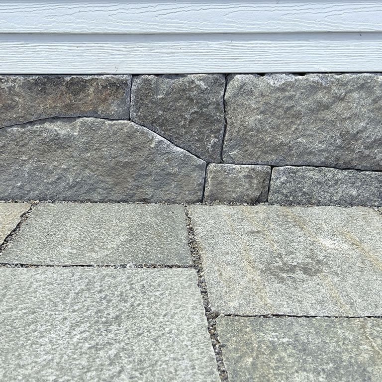 Best close-up image for Reclaimed Granite Thin Veneer. The image shows this product being used in a thin veneer application. The surface finish shown is weathered. Dominant colors shown are beige, gray and tan; with brown, orange/rust, white and cream secondaries. Speckled and random color patterns. Contains some mica.