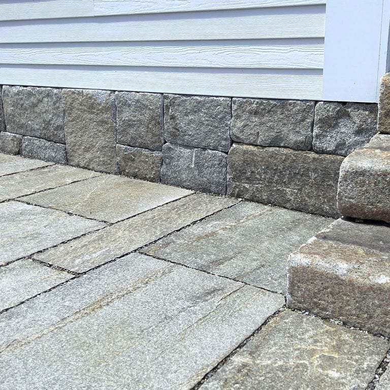 Feature image for Reclaimed Granite Thin Veneer. The image shows this product being used in a thin veneer application. The surface finish shown is weathered. Dominant colors shown are brown and gray; with green, purple, tan and cream secondaries. Exhibits "movement" and the color mix creates a warm feeling. Speckled and blotched color patterns. Contains some mica.