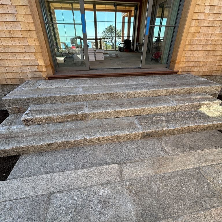 Application image for Reclaimed Footworn Granite - Treads. The image shows this product being used for monolithic steps and treads. The surface finish shown is . The dominant color shown is gray.