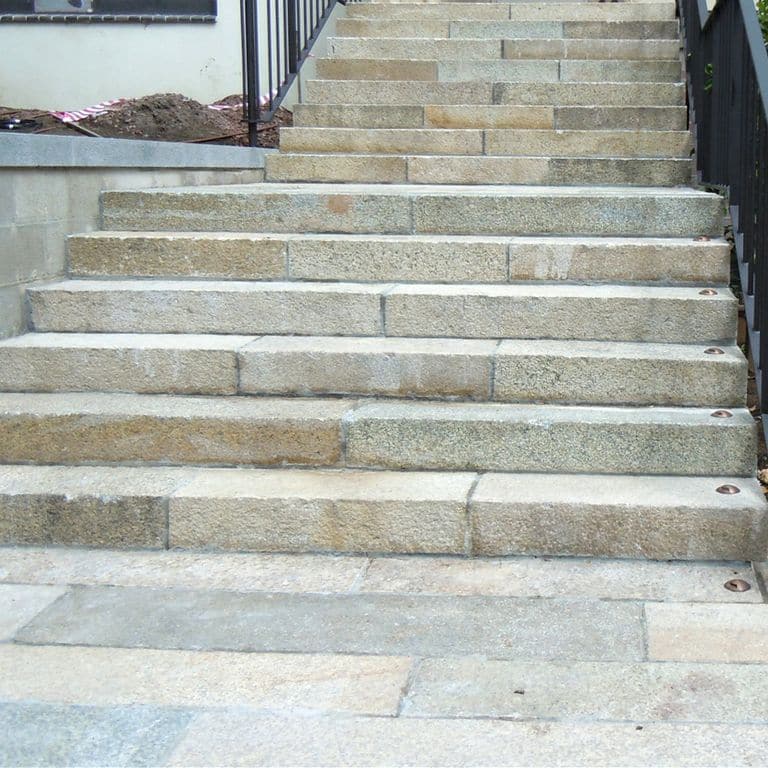 Application image for Reclaimed Footworn Granite - Monolithic Steps. The image shows this product being used in a monolithic steps application. The dominant color shown is gray; with beige, brown, green, orange/rust, pink, white, tan and cream secondaries. Exhibits "movement". Speckled, blotched and cloudy color patterns.