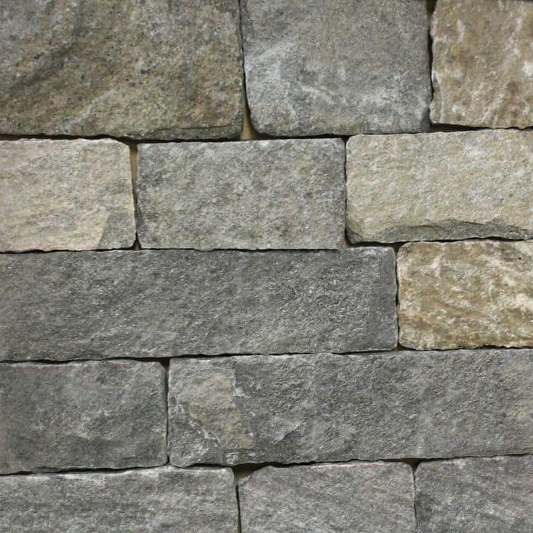 Close-up image for Black Ash Granite - Veneer. The surface finish shown is split-face. Dominant colors shown are green and gray; with brown, orange/rust, purple and tan secondaries. Exhibits "movement" and the color mix creates a warm feeling. Regular and cloudy color patterns.