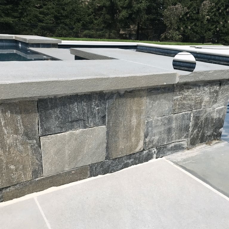 Application image for Black Ash Granite - Veneer. The image shows this product being used for full bed veneer and thin veneer. The surface finish shown is split-face with flat plane. The dominant color shown is gray; with beige, blue, brown, green, purple and white secondaries. The color mix creates a cool feeling. Regular color pattern.