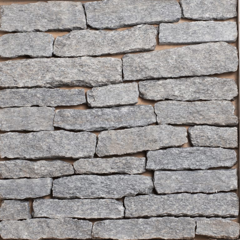 Color/Finish variation image for Bergen Blend Granite - Veneer. The image shows this product being used for full bed veneer and thin veneer. The surface finish shown is split-face. The dominant color shown is gray; with beige, blue, brown, purple and white secondaries. The color mix creates a cool feeling. Streaked and speckled color patterns.