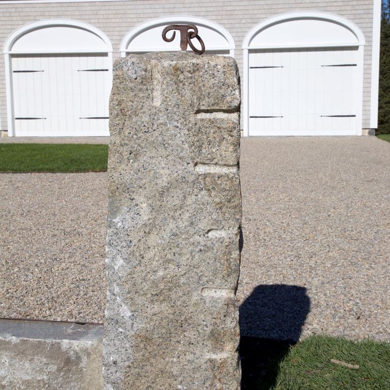 Application image for Reclaimed First Generation Curbstone - Posts. The image shows this product being used in a posts application. The surface finish shown is split-face. The dominant color shown is gray; with beige, brown, orange/rust, purple, white and tan secondaries. Exhibits "movement" and the color mix creates a warm feeling. Swirled, speckled and random color patterns.