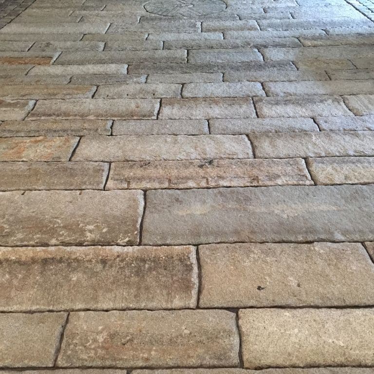 Application image for Reclaimed First Generation Granite Curbstone - Gauged Floor Planks. The image shows this product being used in a patio pavers application. Dominant colors shown are brown, gray and tan. The color mix creates a cool feeling.
