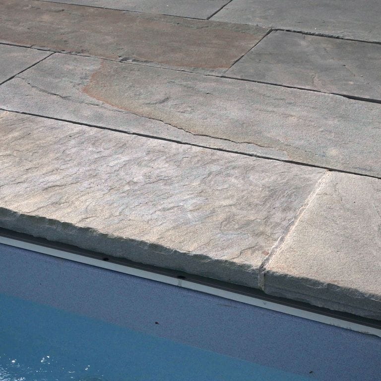 Close-up image for Bluestone Natural Cleft Surface - Blue/Gray - Pool Coping. The surface finish shown is natural cleft. Dominant colors shown are blue and gray; with beige, purple and white secondaries. Exhibits "movement" and the color mix creates a cool feeling. Regular and cloudy color patterns.