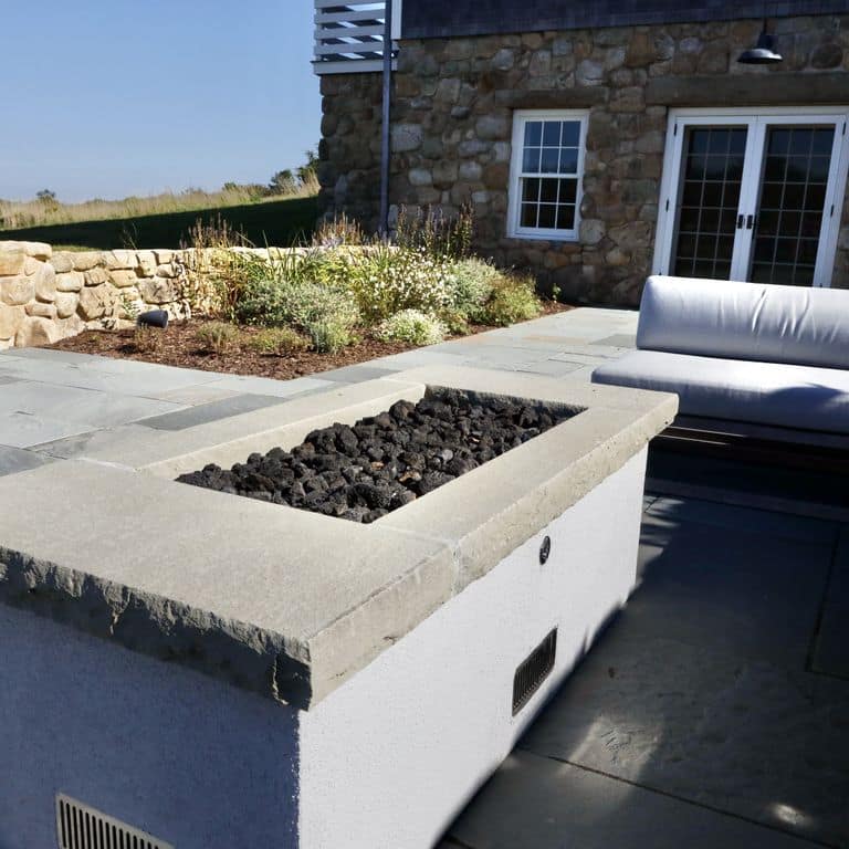 Best close-up image for Bluestone Flamed Surface Blue/Gray Fire Feature. The image shows this product being used in an outdoor fire concepts application. The surface finish shown is flamed. The dominant color shown is gray. The color mix creates a cool feeling. Solid color pattern.