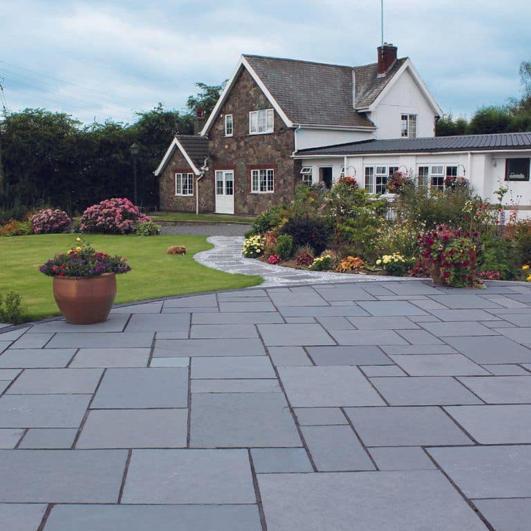 Feature image for Steel Blue Limestone - Pavers. The image shows this product being used for driveway pavers and path pavers. The surface finish shown is a combination of brushed and flamed. Dominant colors shown are blue and gray. The color mix creates a cool feeling. Regular color pattern.