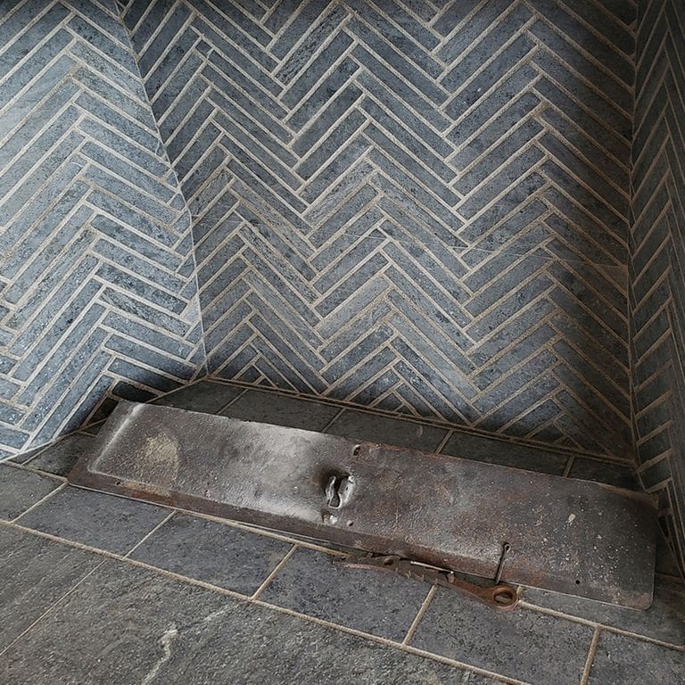 Best close-up image for Curators Soapstone Firebrick. The image shows this product being used in a firebrick application. The surface finish shown is honed. Dominant colors shown are blue and gray; with beige, brown, green, purple and white secondaries. The color mix creates a cool feeling. Regular color pattern.