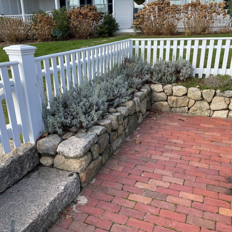 Application image for New England Fieldstone Wallstone - Light. The image shows this product being used in a landscape wallstone application. The surface finish shown is a combination of natural and weathered. The dominant color shown is tan; with beige, brown, gray, orange/rust and cream secondaries. The color mix creates a warm feeling.
