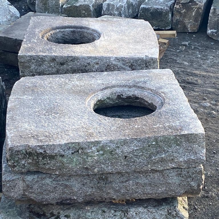 Best close-up image for Reclaimed Granite Manhole Stones. The image shows this product being used for outdoor fire concepts and garden accents. The surface finish shown is a combination of weathered and worn. Dominant colors shown are blue and gray; with pink, purple and white secondaries. The color mix creates a cool feeling. Speckled color pattern.