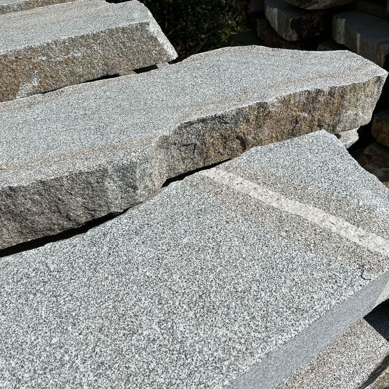 Application image for Dodlin Hill Granite Live Edge Steps - Flamed Tops. The surface finish shown is a combination of flamed and natural. Dominant colors shown are gray and white; with beige, blue, green, pink and cream secondaries. The color mix creates a cool feeling. Speckled color pattern. Contains mineral inclusions.