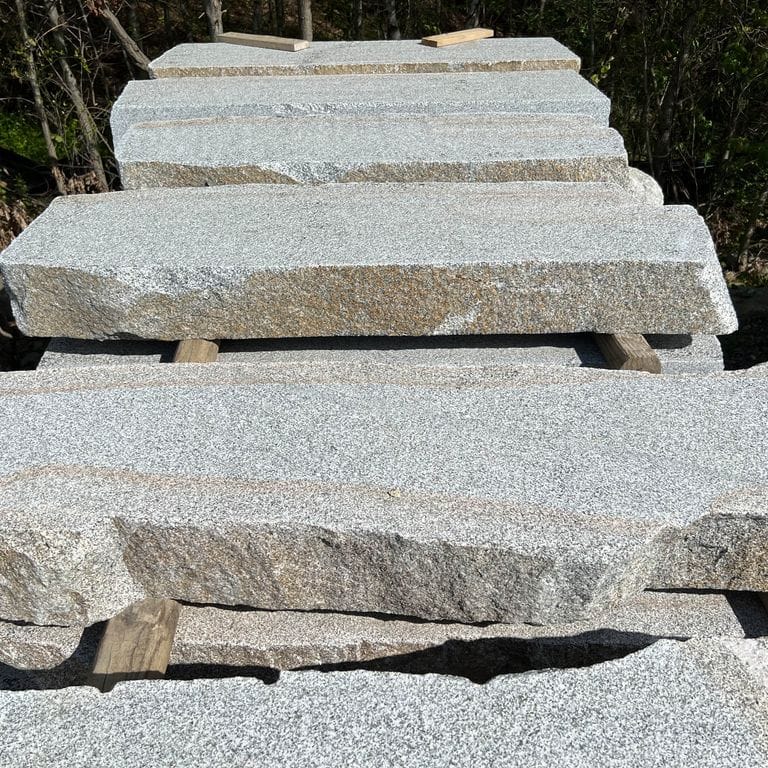 Application image for Dodlin Hill Granite Live Edge Steps - Flamed Tops. The surface finish shown is a combination of flamed and natural. Dominant colors shown are gray and white; with beige, blue, pink and cream secondaries. Speckled color pattern. Contains mineral inclusions.