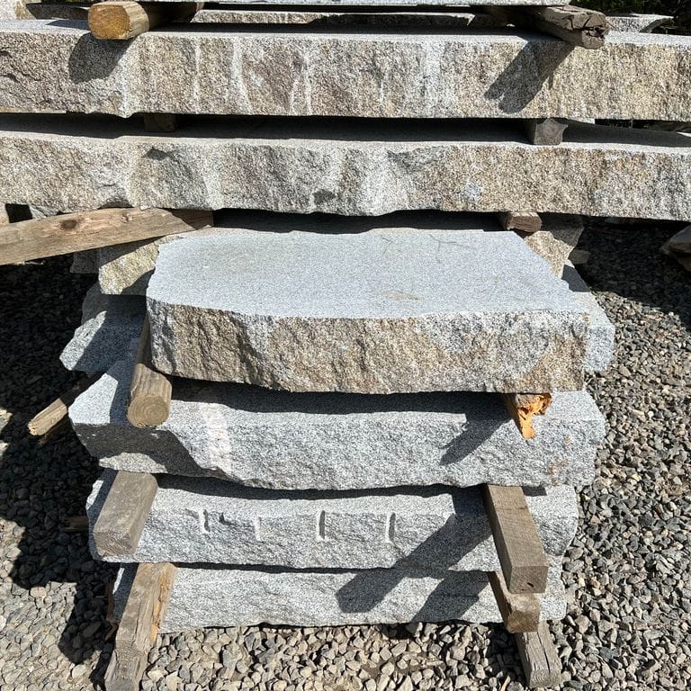 Application image for Dodlin Hill Granite Live Edge Steps - Flamed Tops. The surface finish shown is a combination of flamed and natural. Dominant colors shown are gray and white; with beige, blue, brown, pink, purple, tan and cream secondaries. The color mix creates a cool feeling. Speckled color pattern.