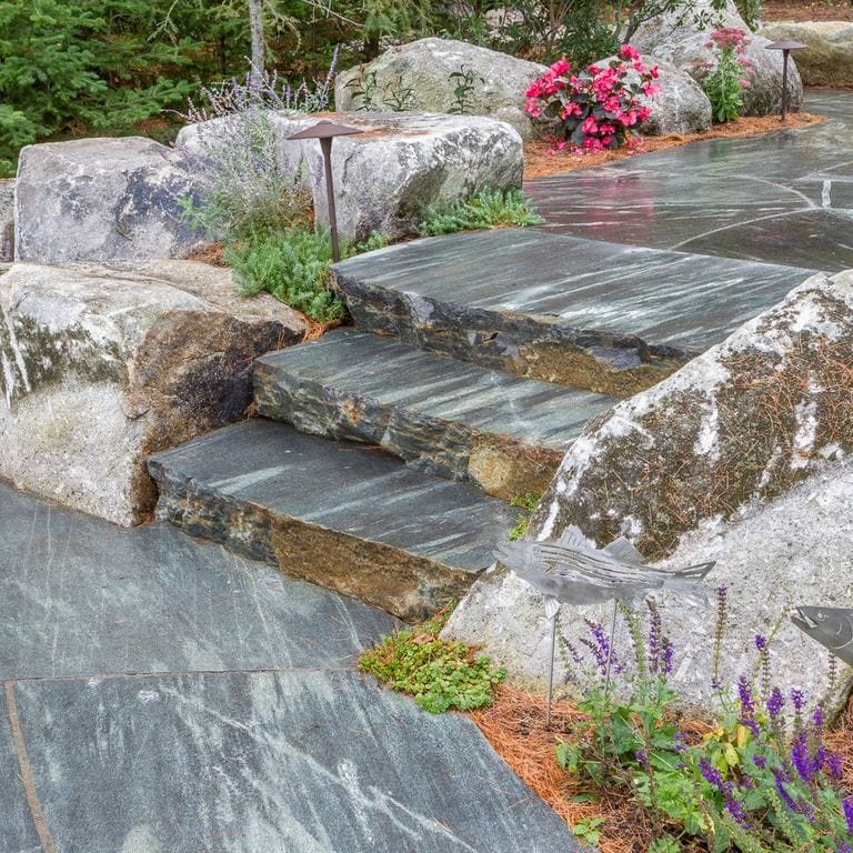 Feature image for Mystic Mountain Live Edge Steps. The image shows this product being used in a monolithic steps application. The dominant color shown is gray; with blue, brown and green secondaries. Exhibits "movement" and the color mix creates a cool feeling. Random, linear and streaked color patterns.