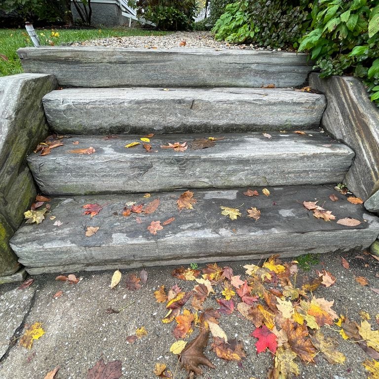 Application image for Mystic Mountain Live Edge Steps. The image shows this product being used in a monolithic steps application. The surface finish shown is flamed. The dominant color shown is gray; with green and white secondaries. Exhibits "movement" and the color mix creates a cool feeling. Linear and streaked color patterns.