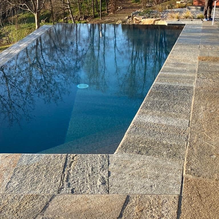 Application image for Pietra Italia Full Color Gneiss - Pool Coping. The image shows this product being used in a pool coping application. The surface finish shown is natural cleft. Dominant colors shown are gray and tan. The color mix creates a warm feeling.