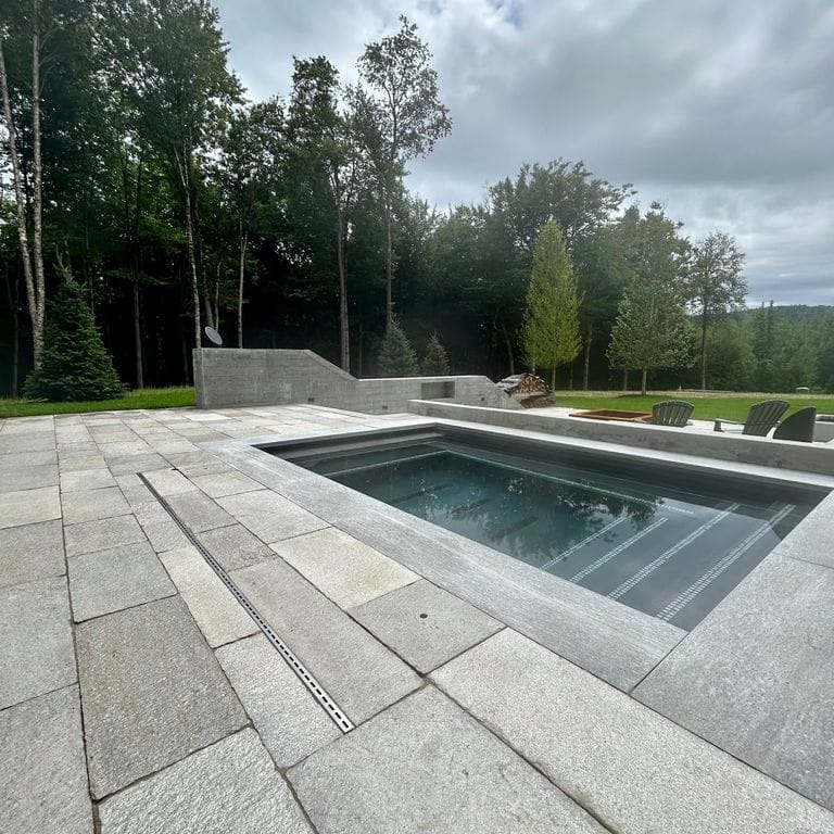 Application image for Pietra Italia Gneiss - Pool Deck. The image shows this product being used in a pool deck pavers application. The surface finish shown is natural cleft. The dominant color shown is gray. The color mix creates a cool feeling.