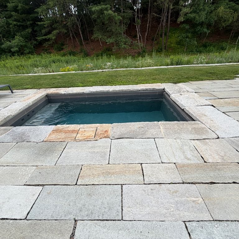 Application image for Pietra Italia Gneiss - Natural Cleft - Pool Deck. The image shows this product being used for patio pavers and pool deck pavers. The surface finish shown is natural cleft. Dominant colors shown are gray and greige. The color mix creates a warm feeling.