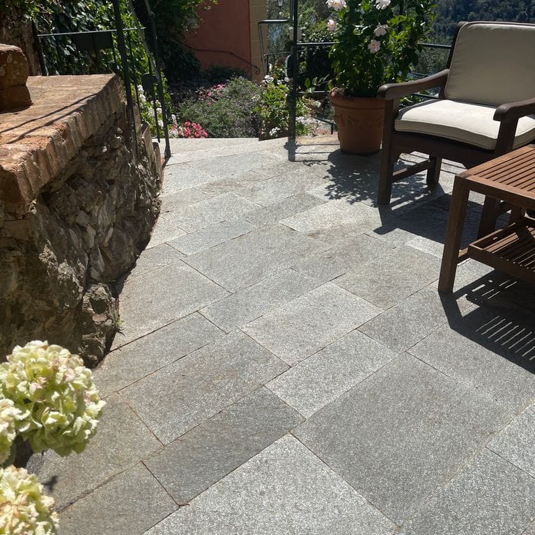 Application image for Pietra Italia Full Color Gneiss - Pavers. The image shows this product being used in a patio pavers application. The surface finish shown is natural cleft. The dominant color shown is gray. The color mix creates a warm feeling.