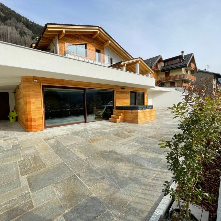 Application image for Pietra Italia Gneiss - Natural Cleft Pavers. The image shows this product being used in a patio pavers application. The surface finish shown is natural cleft. Dominant colors shown are gray and tan. The color mix creates a warm feeling.