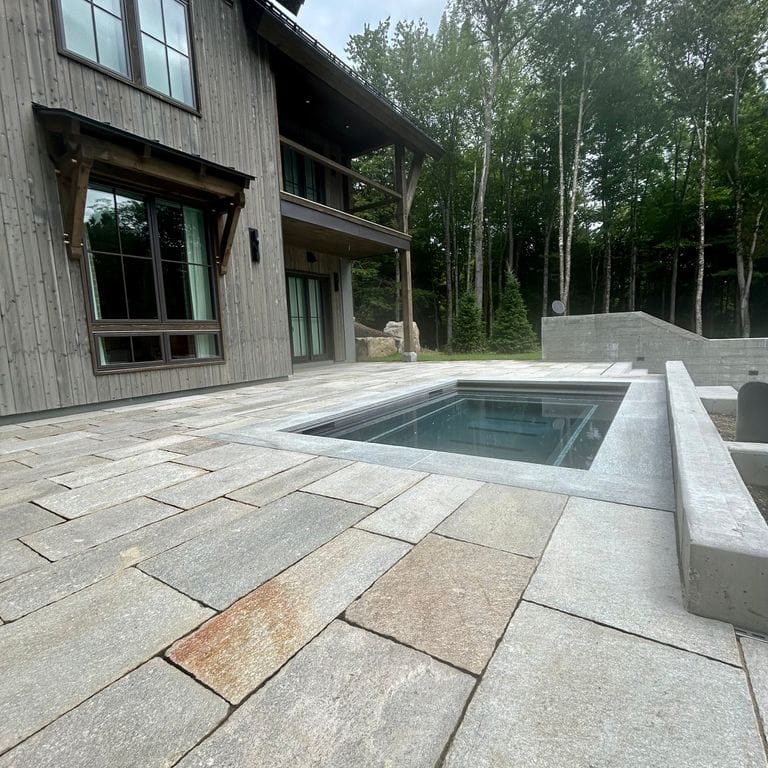 Application image for Pietra Italia Gneiss - Natural Cleft Pavers. The image shows this product being used for pool coping and pool deck pavers. The surface finish shown is natural cleft. The dominant color shown is gray. The color mix creates a warm feeling.