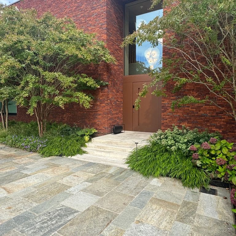 Application image for Pietra Italia Gneiss - Natural Cleft Pavers. The image shows this product being used in a patio pavers application. The surface finish shown is natural cleft. Dominant colors shown are gray and tan. The color mix creates a warm feeling.