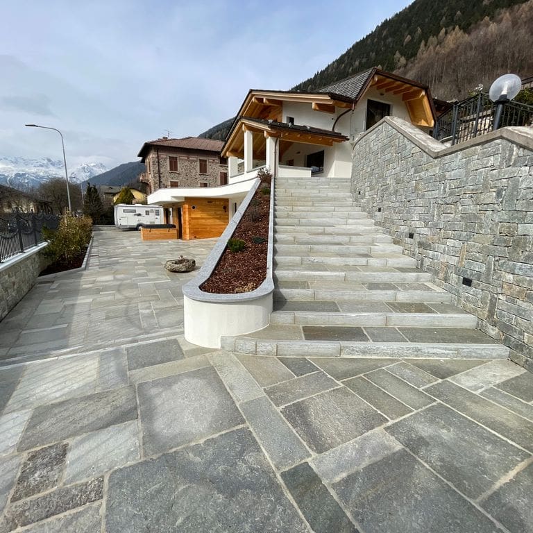 Application image for Pietra Italia Gneiss - Natural Cleft Pavers. The image shows this product being used in a patio pavers application. The surface finish shown is natural cleft. Dominant colors shown are gray and tan. The color mix creates a warm feeling.