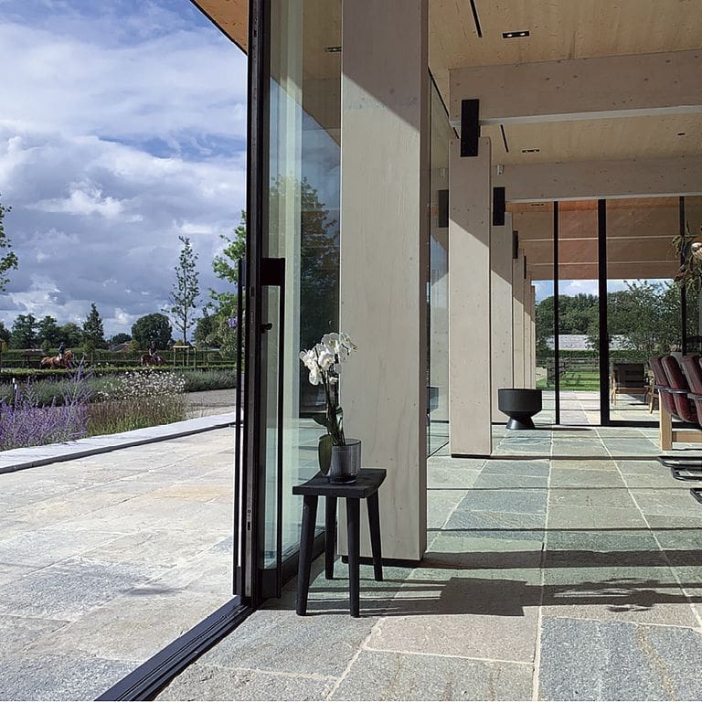 Application image for Pietra Italia Gneiss - Natural Cleft Pavers. The image shows this product being used in a patio pavers application. The surface finish shown is natural cleft. Dominant colors shown are gray and tan. The color mix creates a warm feeling.