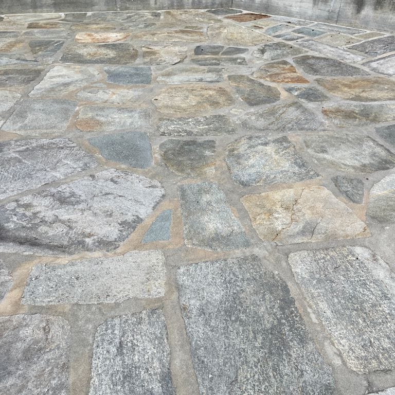 Application image for Pietra Italia Full Color Gneiss - Irregular Pavers. The image shows this product being used in a patio pavers application. The surface finish shown is natural cleft. Dominant colors shown are beige and gray. The color mix creates a warm feeling.