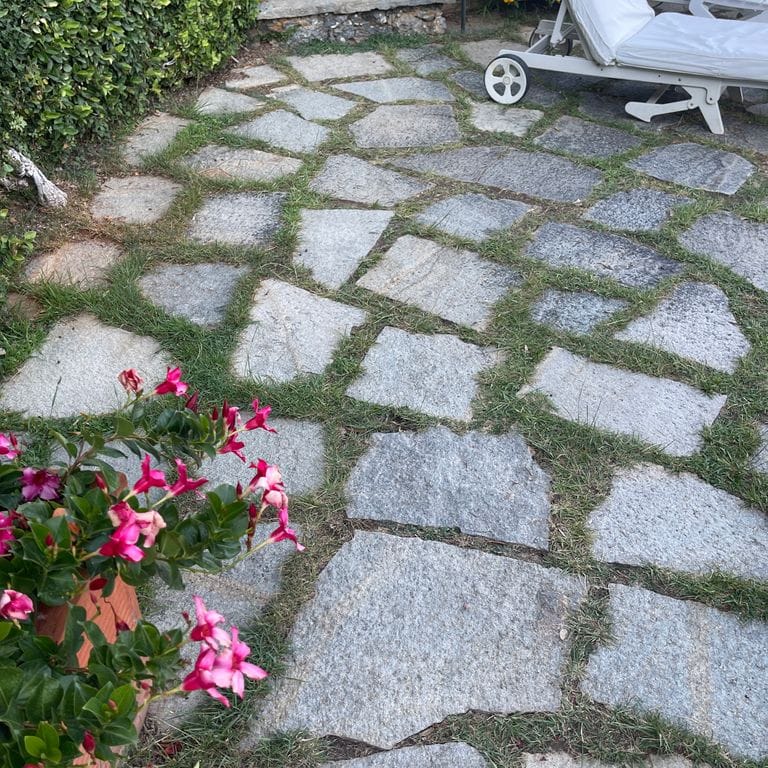 Application image for Pietra Italia Full Color Gneiss - Irregular Pavers. The image shows this product being used in a patio pavers application. The surface finish shown is natural cleft. Dominant colors shown are gray and tan. The color mix creates a warm feeling.