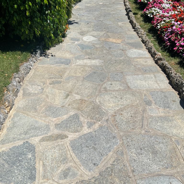 Application image for Pietra Italia Full Color Gneiss - Irregular Pavers. The image shows this product being used in a path pavers application. The surface finish shown is natural cleft. Dominant colors shown are beige and gray. The color mix creates a warm feeling.