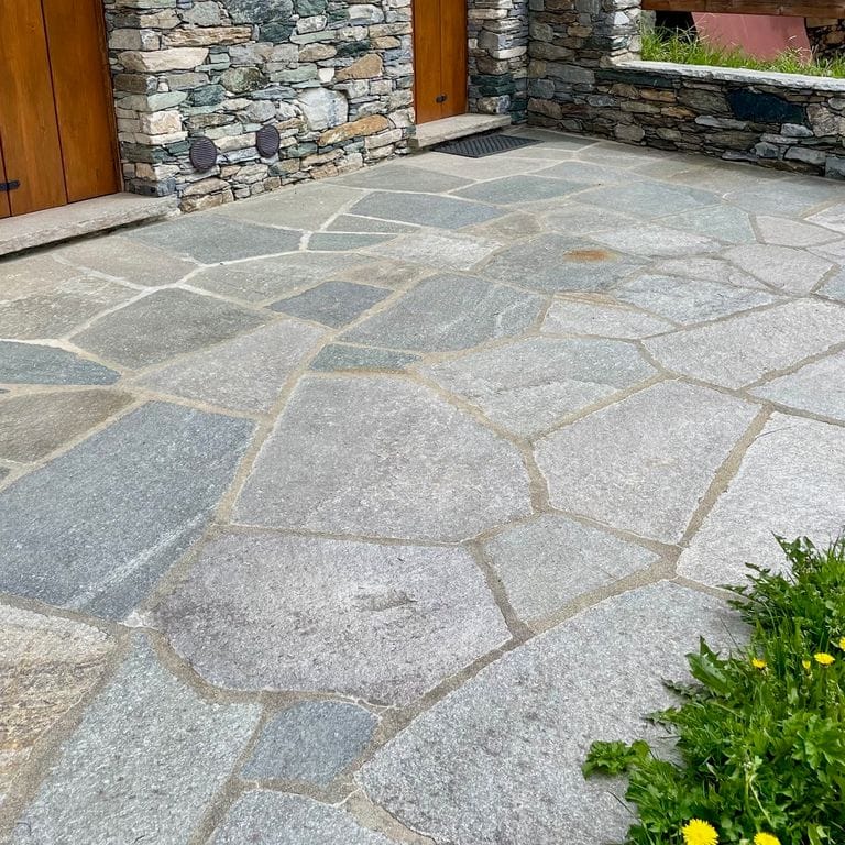 Application image for Pietra Italia Gneiss - Natural Surface Irregular Pavers. The image shows this product being used in a patio pavers application. The surface finish shown is natural cleft. The dominant color shown is gray. The color mix creates a warm feeling.