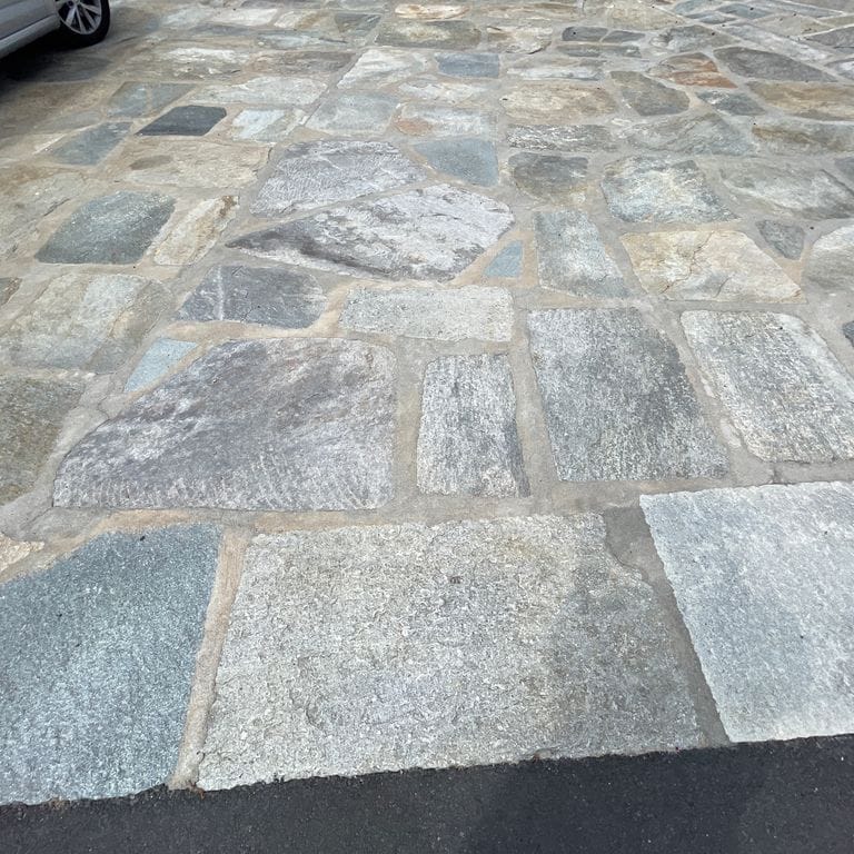 Application image for Pietra Italia Full Color Gneiss - Irregular Pavers. The image shows this product being used in a patio pavers application. The surface finish shown is natural cleft. Dominant colors shown are beige and gray. The color mix creates a warm feeling.