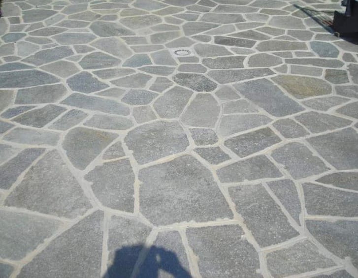 Application image for Pietra Italia Gneiss - Natural Surface Irregular Pavers. The image shows this product being used in a patio pavers application. The surface finish shown is natural cleft. The dominant color shown is gray. The color mix creates a cool feeling.