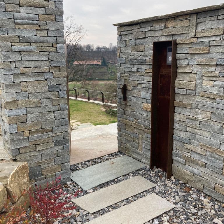 Application image for Pietra Italia Full Color Gneiss - Veneer. The image shows this product being used for path pavers, full bed veneer and thin veneer. The surface finish shown is split-face. Dominant colors shown are beige and gray; with black, brown, orange/rust, purple, white and tan secondaries. The color mix creates a warm feeling. Regular and linear color patterns.