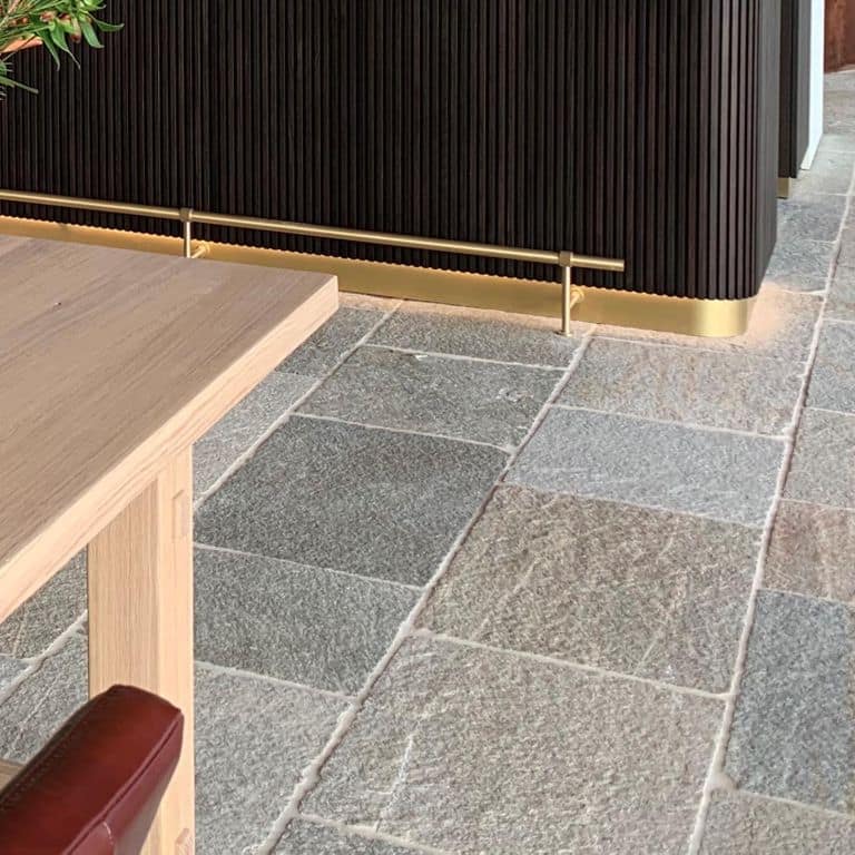 Best close-up image for Pietra Italia Full Color Gneiss - Natural Cleft &amp; Brushed Interior Floor. The image shows this product being used in an interior floor application. The surface finish shown is natural cleft. Dominant colors shown are beige, gray and tan; with blue, brown, orange/rust, pink, purple, white and cream secondaries. The color mix creates a warm feeling. Regular, fine speckled and random color patterns. Contains some mica and mineral inclusions.