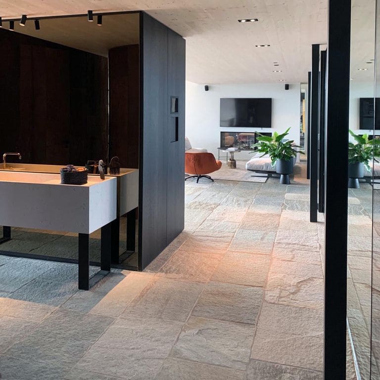 Feature image for Pietra Italia Full Color Gneiss - Natural Cleft &amp; Brushed Interior Floor. The image shows this product being used in an interior floor application. The surface finish shown is natural cleft. Dominant colors shown are beige and gray; with green, orange/rust, pink, purple, white, tan and cream secondaries. The color mix creates a warm feeling. Regular, linear and random color patterns.