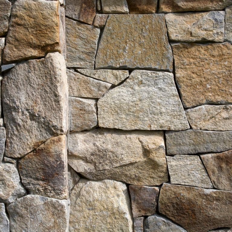 Best close-up image for Black Mountain Granite Natural - Thin Veneer. The image shows this product being used in a thin veneer application. The surface finish shown is split-face. Dominant colors shown are brown and gray; with beige, green, orange/rust, purple, white and tan secondaries. Speckled, blotched and random color patterns. Contains some mica.