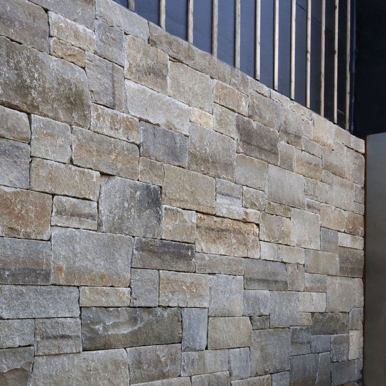 Application image for Reclaimed Granite Curbstone - Full Bed Veneer. The image shows this product being used in a full bed veneer application. The surface finish shown is . Dominant colors shown are gray and tan. Regular, speckled and blotched color patterns.