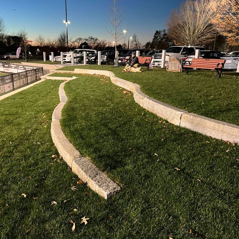 Feature image for Reclaimed Granite Curbstone - Radius Curve. The image shows this product being used in a landscape curbing &amp; edging application. The surface finish shown is a combination of ,  and . Dominant colors shown are gray and tan. The color mix creates a warm feeling.
