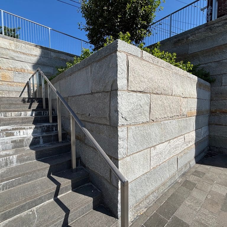 Application image for Reclaimed Granite Curbstone - Plank Veneer. The image shows this product being used in a full bed veneer application. The surface finish shown is . Dominant colors shown are gray and tan. The color mix creates a cool feeling.