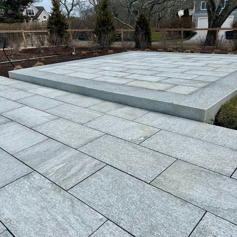 Feature image for Pietra Italia Gneiss - Sawn Pavers. The image shows this product being used in a patio pavers application. The surface finish shown is sand blasted. Dominant colors shown are blue and gray. The color mix creates a cool feeling.