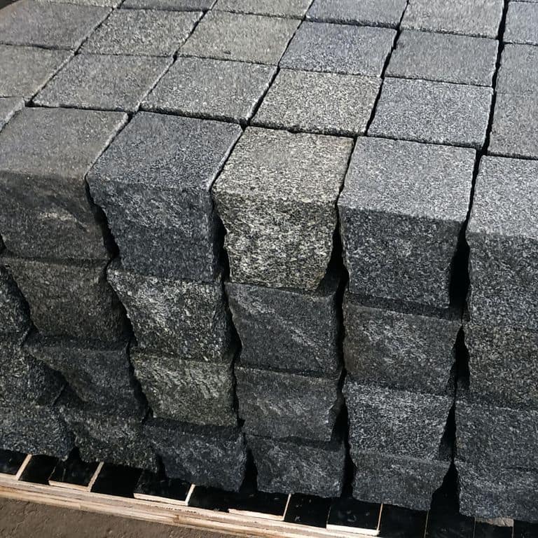 Best close-up image for Tai Black Granite Cobblestones. The surface finish shown is a combination of flamed and split-face with flat plane. The dominant color shown is gray. The color mix creates a cool feeling. Regular and speckled color patterns.