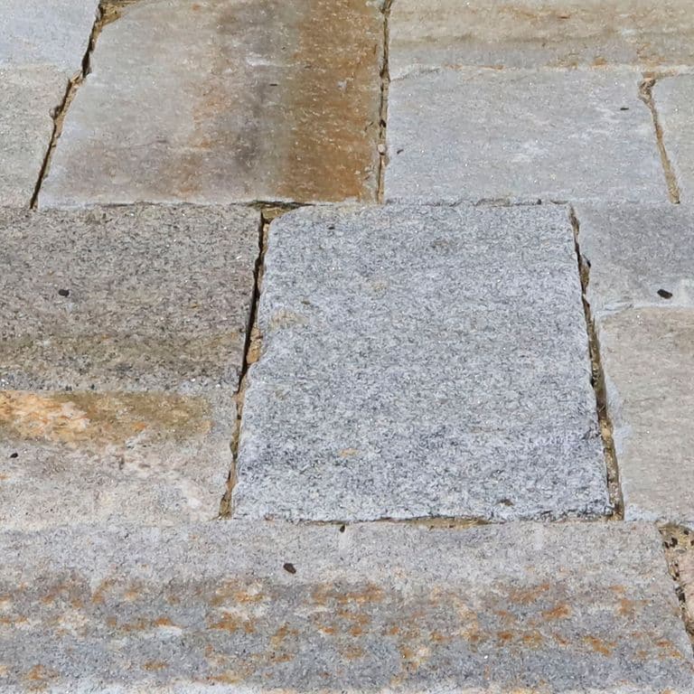 Best close-up image for Reclaimed Granite Curbstone Plank Paver Mix - Random Widths and Lengths to 36". The image shows this product being used in a path pavers application. The surface finish shown is . The dominant color shown is gray. The color mix creates a warm feeling. Speckled color pattern.